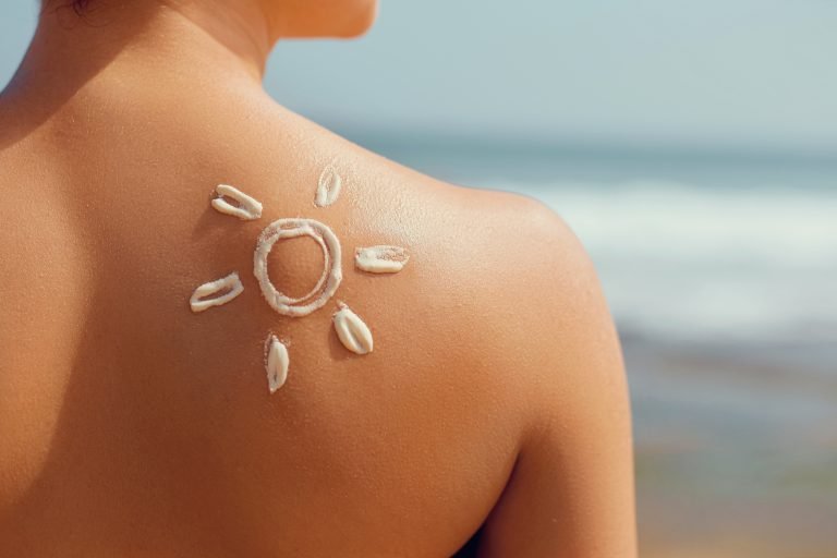 sunscreen on woman's body shape of sun facing the sea